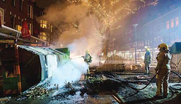 Firefighters work to extinguish a fire on the Groene Hilledijk in Rotterdam, late on Monday, after a second wave of riots in the Netherlands following the introduction of a coronavirus curfew over the weekend.