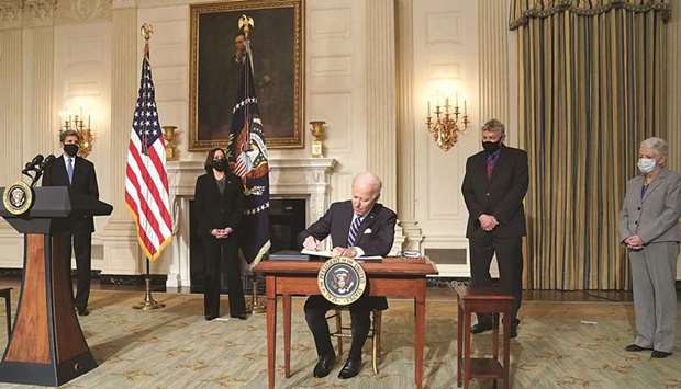 US President Joe Biden signs executive orders on tackling climate change as members of his climate team and Vice President Kamala Harris stand behind in the State Dining Room at the White House in Washington, US, yesterday.