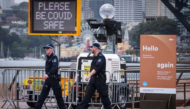 New South Wales police officers walk past signs on display in front of the Opera House as Covid-19 restrictions are enforced for New Year celebrations around Circular Quay in central Sydney