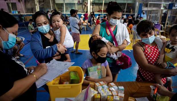 Mothers and their children wearing masks for protection against the coronavirus disease (Covid-19) wait for free vitamins and medicine at a local health center in Manila, Philippines
