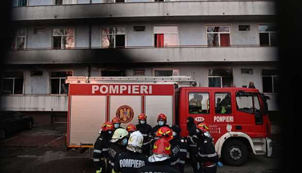 Firemen gather in the courtyard of the Matei Bals infectious diseases hospital's burned pavilion in Bucharest