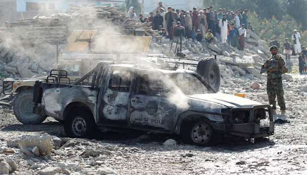An Afghan National Army soldier inspects the wreckage of a burnt army car at the site of a blast