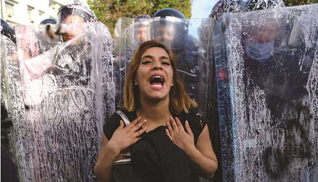 A Tunisian woman reacts as she stand in front of police officers forming a human shield to block the access to demonstrators to the centre of the capital Tunis during a rally to denounce police brutality yesterday.