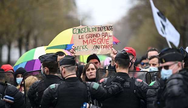 A demonstrator holds a sign reading u2018Defence Council, the great masked ball, so ... letu2019s danceu2019 as she stands in front of French Gendamres during a demonstration in Paris against the draft u2018global securityu2019 law, which would restrict publication of pictures showing the faces of police officers on duty.