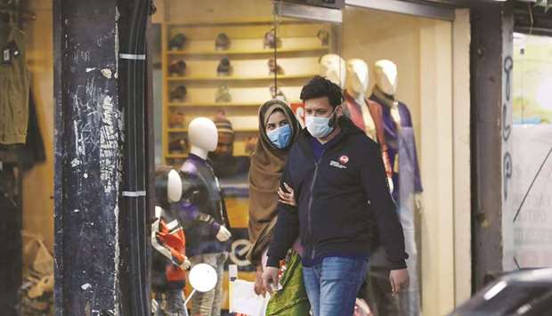 PROTECTION: A couple wearing protective masks walk along a market amid the outbreak of coronavirus disease in the south port city of Karachi. (Reuters)