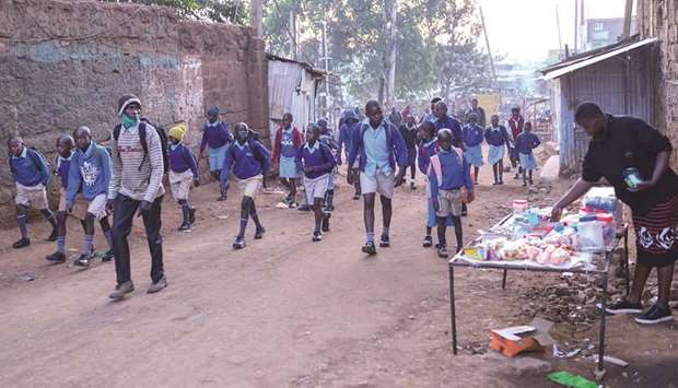 Students walk towards their school in the early morning of the official reopening day of public schools, yesterday, in Kibera slum.