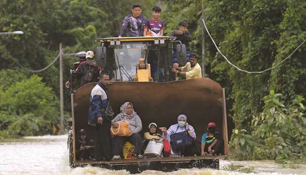 Residents ride a digger vehicle through floodwaters following heavy monsoon downpour in Lanchang, Malaysiau2019s Pahang state, yesterday.