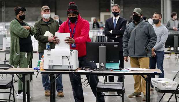 A Fulton County election worker puts absentee ballots in a scanner as election observers look on, at the Georgia World Congress Center in Atlanta, Georgia