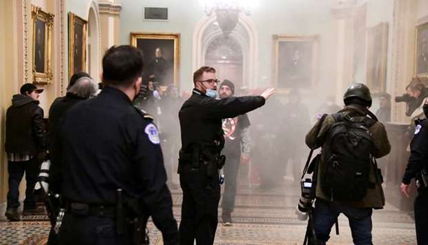 Supporters of President Donald Trump set off a fire extinguisher after breaching security defenses, as police move in on the demonstrate on the second floor of the US Capitol near the entrance to the Senate, in Washington