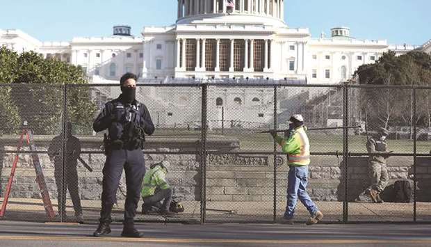 Workers erect a fence yesterday around the US Capitol Building, the day after a mob broke into the building in Washington, DC.