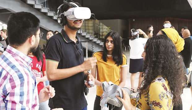 A group of Northwestern Qatar students using VR glasses to showcase their film projects.rnrn