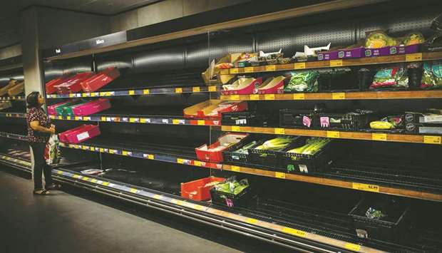 A lone shopper surveys cleared out shelves in the wake of panic buying in Brisbane yesterday.