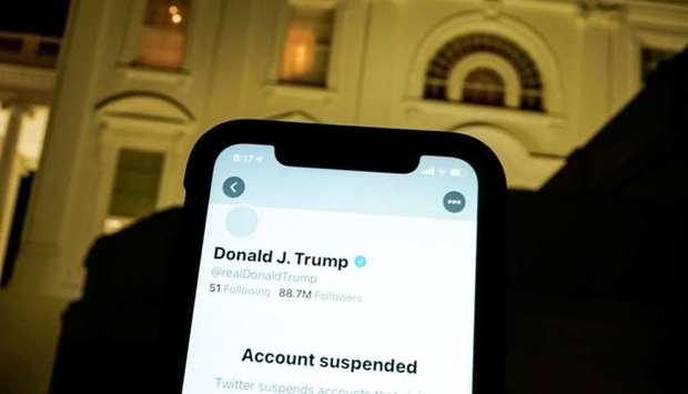 A photo illustration shows the suspended Twitter account of US President Donald Trump on a smartphone and the White House in Washington. Reuters