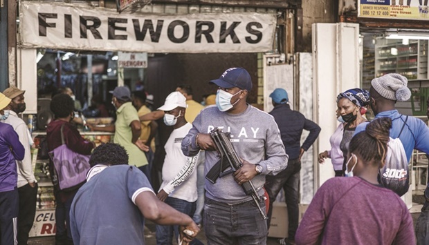 A police officer is seen in this picture taken on Thursday as customers queue to buy fireworks outside the St Mary Cathedral in Johannesburg.