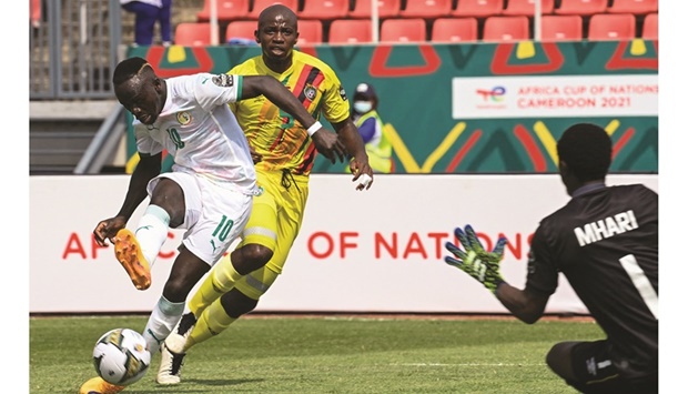 Senegalu2019s forward Sadio Mane shoots to score as Zimbabweu2019s goalkeeper Petros Mhari (right) prepares to make a save during the Group B Africa Cup of Nations 2021 match at Stade de Kouekong in Bafoussam, Cameroon, yesterday. (AFP)