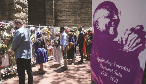 Family members of late Archbishop Desmond Tutu walk past a remembrance wall of flowers and condolence messages left by members of the public, outside the St Georges Cathedral in Cape Town.