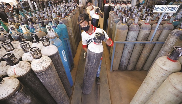 People carry oxygen cylinders after refilling them in a factory yesterday, amidst the spread of Covid-19 in Ahmedabad, India.