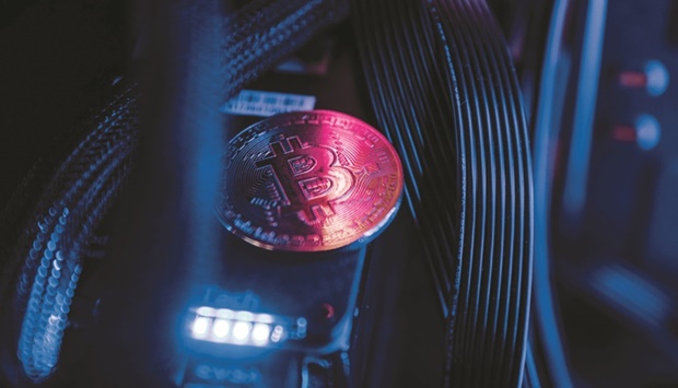 A token representing Bitcoin virtual currency sits among cables and LED lighting inside a u2018mining rigu2019 computer in an arranged photograph in Budapest. Bitcoin ended a banner year with a rocky finish. The largest cryptocurrency by market value closed out December with a 19% drop, its largest monthly loss since May.