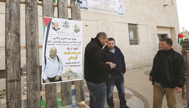 Men stand next to a poster of Palestinian Omar Abdalmajeed Asu2019ad, 80, in Jiljilya village in the occupied West Bank, yesterday.