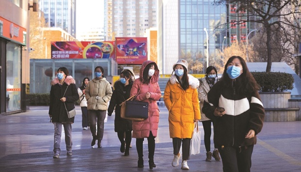 People walk on a street as the coronavirus disease outbreak continues in Beijing on January 13. Chinese leaders have pledged more support for the slowing economy, which is facing a fresh challenge from the recent local spread of the highly-contagious Omicron variant