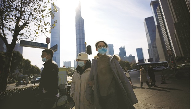 People wearing protective masks walk on a street, following new cases of the coronavirus disease (Covid-19), in Shanghai, China.