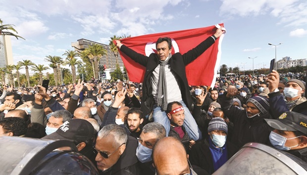 A Tunisian man waves his countryu2019s national flag during protests against President Kais Saied, on the 11th anniversary of the revolution in the capital Tunis, yesterday.