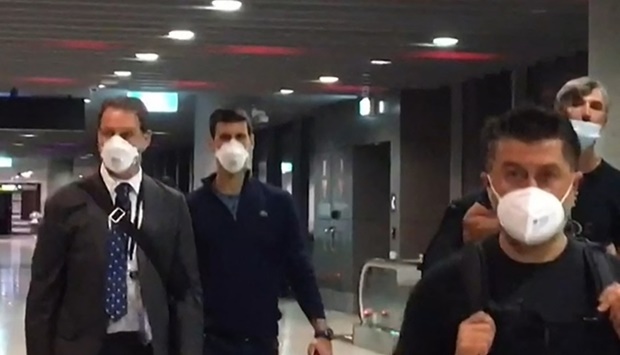 This screen grab taken from AFPTV shows Serbia's Novak Djokovic (2nd L) preparing to depart from Melbourne Airport in Melbourne on January 16, 2022, after losing a sensational legal battle over his coronavirus vaccination status with his dream of clinching a record 21st Grand Slam in tatters. Mell CHUN / AFP