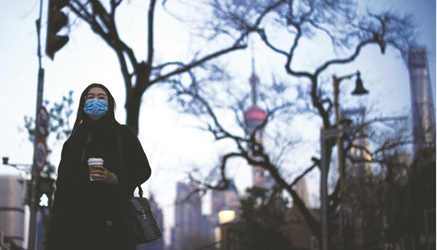 A woman wearing a protective face mask walks on a street, following new cases of the coronavirus  disease (Covid-19), in Shanghai yesterday. With the property sectoru2019s downturn seen persisting into 2022 and the fast-spreading Omicron variant dampening consumer activity, many analysts say monetary easing measures will be necessary, even as other major economies, including the United States, appear set to tighten monetary policy this year.