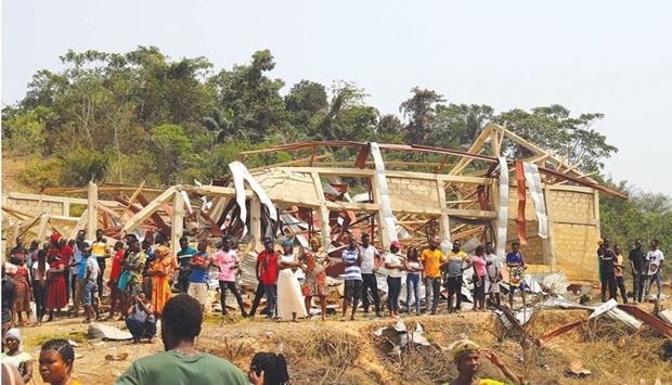 People standing by debris of house and buildings that were destroyed when a vehicle carrying mining explosives detonated along a road in Apiate, yesterday.