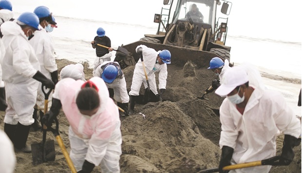 Workers clean an area affected by the oil spill in Ancon.