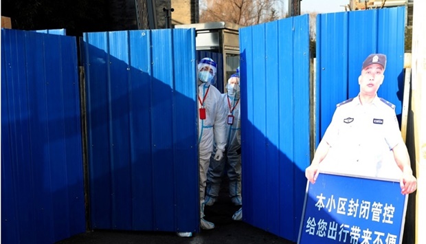 Workers wearing protective suits following the coronavirus disease outbreak stand at an entrance to a residential compound under lockdown after a case of the Omicron variant was detected, in Beijing's Haidian district, China, January 18. China Daily via REUTERS