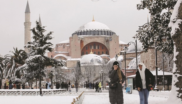 Tourists walk along Sultanahmet Square as Hagia Sophia Grand Mosque is seen in the background during a snowy day in Istanbul yesterday. (Reuters)