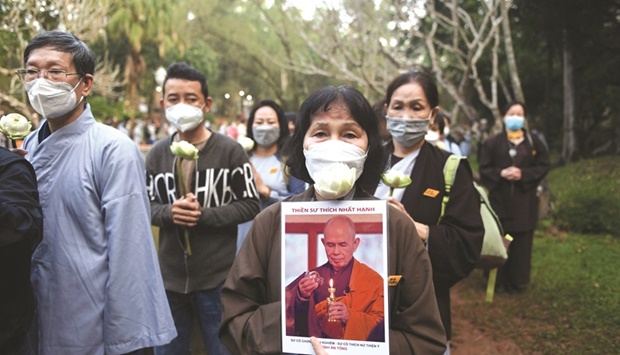 A mourner holds a portrait of Vietnamese monk Thich Nhat Hanh during the procession to a cremation ground in Hue province yesterday.