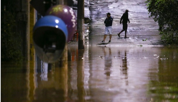 People stand in a flooded street after heavy rain in Caieiras, Brazil January 30. REUTERS