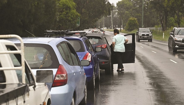 A woman in line at a coronavirus Covid-19 testing centre steps out of her vehicle to look at the queue of traffic blocking a Western Sydney highway in Sydney, Australia.