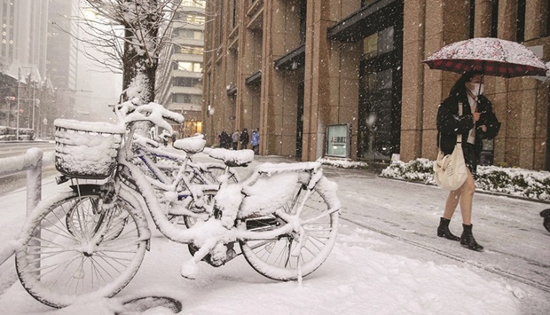 A pedestrian walks past snow-covered bicycles in Tokyo yesterday.