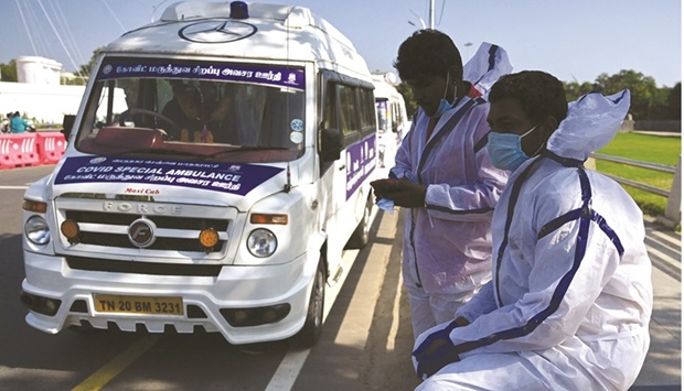 Ambulance support staff wearing Personal Protective Equipment (PPE) prepare for their work shift next to newly inducted Covid special ambulances in Chennai yesterday.