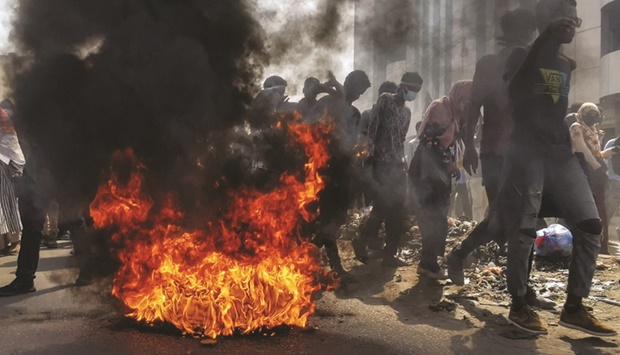 Protesters rallying against the military walk past burning tyres in Khartoum.
