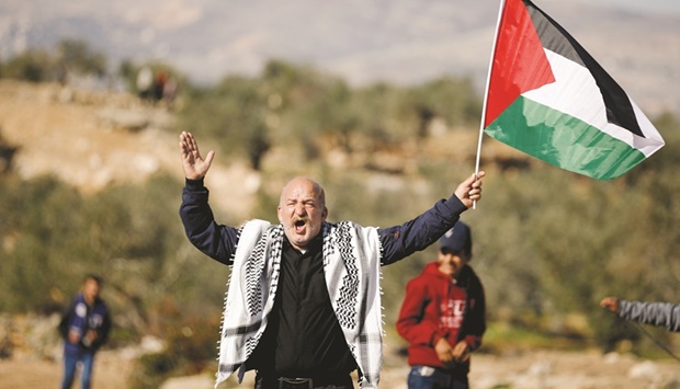 A man holding a Palestinian flag gestures during a protest against Israeli settlements, in Beita, in the occupied West Bank, yesterday.