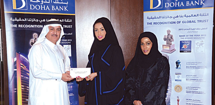 Doha Banku2019s Khalid al-Naama handing the cheque to the Qatar Paralympic Committeeu2019s Sara al-Dossari.