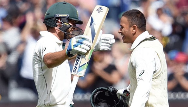 Australian batsman Joe Burns (L) and Usman Khawaja (R) celebrate scoring centuries against the West Indies on the first day of the second Test in Melbourne yesterday. (AFP)