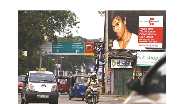Sri Lankan commuters pass by a billboard in Colombo yesterday, associated with a concert of the Latin pop star Enrique Iglesias.