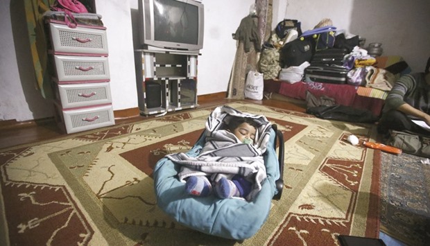 A Syrian baby sleeps in his cradle on the floor while his mother (partially seen) takes part in an interview with Reuters in Istanbul.