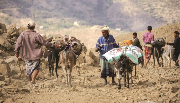 Yemenis accompany their donkeys carrying food parcels as they walk through the mountains along the only path accessible between the southern cities of Aden and Taez yesterday.