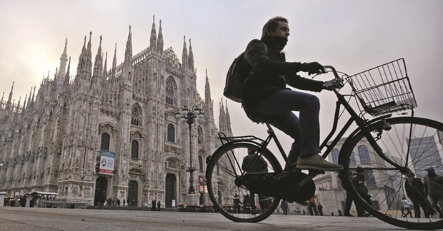 A man rides his bicycle near the Duomo in Milan yesterday. Drivers in Milan will face a limit on daytime travel for three days as the northern Italian city tries to bring air pollution down from dangerous levels.