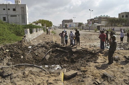 People gather around a crater caused by a Saudi-led air strike in Yemenu2019s Red Sea port city of Houdieda yesterday.
