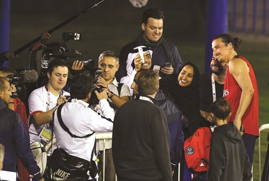 PSG striker Zlatan Ibrahimovic (right) poses for photographs with fans after a training session yesterday. PICTURE: Anas Khalid