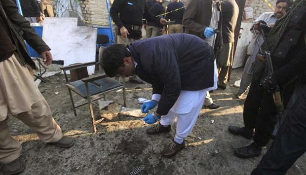 A forensic officer collects evidence from the site of a suicide attack at a government office in Mardan on Tuesday.