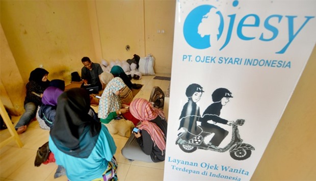 Female motorbike taxi drivers learning how to take orders from their smartphones at an office in Jak