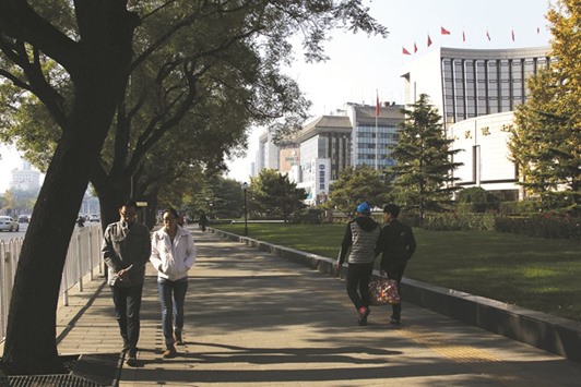 Pedestrians walk past the Peopleu2019s Bank of China headquarters (right), in the financial district of Beijing. The PBoC has suspended at least three foreign banks from conducting some foreign exchange business until the end of March.
